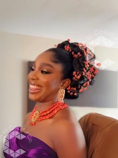 a woman in a purple dress with orange beads on her head and necklaces around her neck