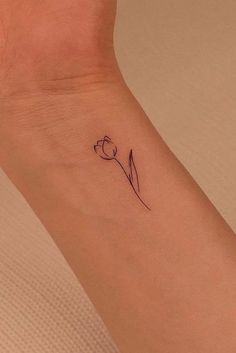 a small tattoo on the wrist of a woman with a single tulip in it