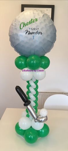 a golf themed balloon sculpture on top of a table with a golf ball and tee