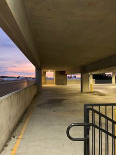 an empty parking garage with the sun setting in the distance and no one around it