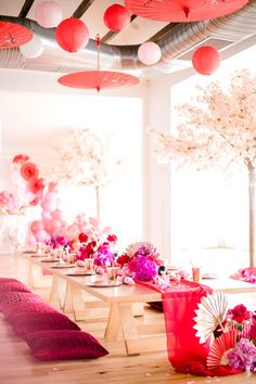 the tables are set up with pink and red flowers in vases, paper fans, and lanterns