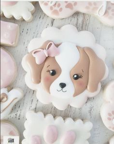 decorated cookies with pink and white icing are on a wooden surface, including one dog's face