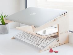 an apple laptop sitting on top of a wooden stand with a keyboard and mouse in front of it