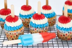 cupcakes with red, white and blue frosting on a cooling rack next to toothbrushes