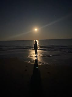 a person standing on the beach at night