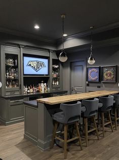 a home bar with grey cabinets and stools