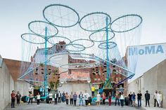 a group of people standing in front of a building with large metal circles on it