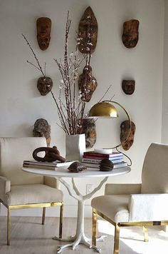 a white table topped with books next to two chairs and a vase filled with flowers