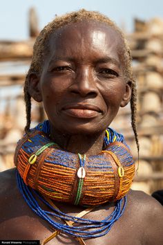 an african woman with braids and beads on her neck, looking at the camera