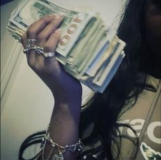 a woman is holding money in her hand and wearing chain around her neck with both hands