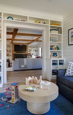 a living room filled with furniture and bookshelves next to a blue carpeted floor