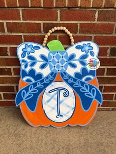 an orange and blue handbag with a large bow on it's back hanging from a brick wall