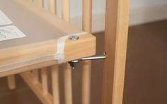 a wooden crib with a white sheet on the bottom and an ironing board attached to it