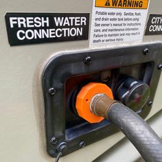 an orange and black hose connected to a water heater with warning signs on it