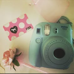 a blue camera sitting next to a pink flower