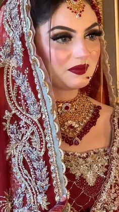 a woman wearing a red and gold bridal outfit