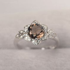 an engagement ring with a large brown stone surrounded by white diamonds on a gray background