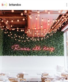 the inside of a restaurant with lights hanging from the ceiling and greenery on the walls