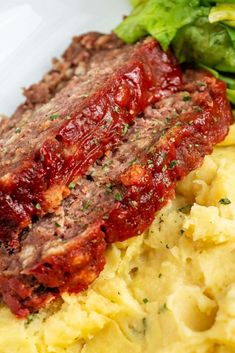 meatloaf and mashed potatoes on a plate with lettuce in the background