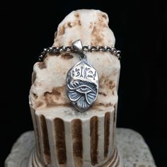 a close up of a cake on a table with a chain around it and an eye charm hanging from the top