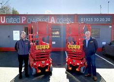 two men standing next to each other in front of a large red truck with the words united pyrland access on it