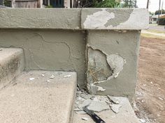 a broken up concrete wall next to a black baseball bat on the ground in front of a house