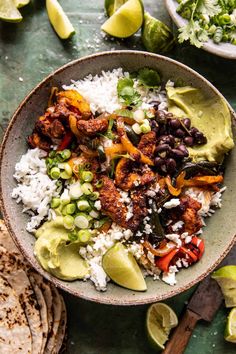 a bowl filled with rice, black beans and avocado next to tortillas