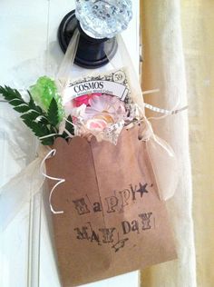 a brown paper bag with some flowers and other items in it sitting on a window sill