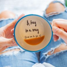 a person holding a coffee mug with writing on the inside and in between their legs