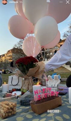 a table topped with lots of balloons and cake next to a basket filled with flowers