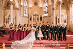 a group of people in formal wear posing for a photo at a church with the bride and groom