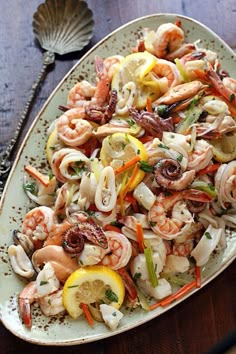 a plate filled with shrimp and vegetables on top of a wooden table next to utensils