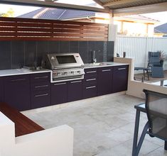 an outdoor kitchen with a grill, sink and dining room table in the back yard