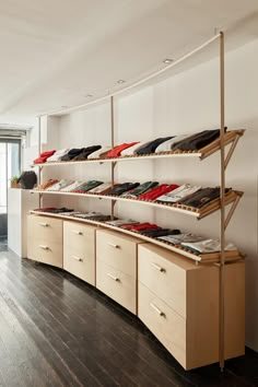 the shelves are filled with different types of shoes and clothing on wooden flooring in front of a large window