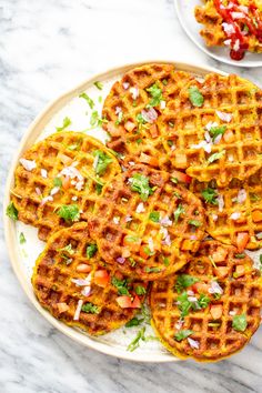 three waffles on a plate with toppings and a bowl of salad in the background