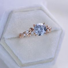 an engagement ring with blue and white stones in it on top of a white cloth