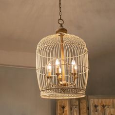 a chandelier hanging from the ceiling with three candles in it and a birdcage