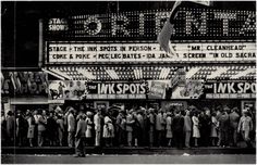 an old black and white photo of people standing in front of a theater