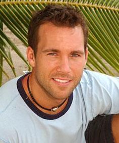 a man is smiling for the camera with palm trees in the back ground behind him