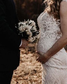 a bride and groom holding hands during their wedding ceremony in the woods, with dried leaves on the ground