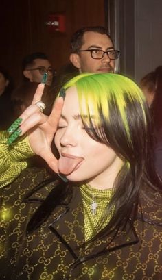 a woman with bright green hair making a peace sign while standing next to other people