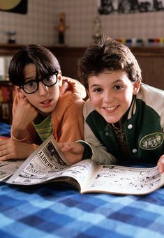 two young boys laying on top of an open book