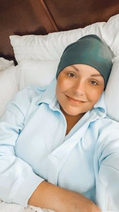 a woman laying on top of a bed wearing a blue shirt and headband with her arms crossed