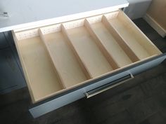 an open drawer in a kitchen next to a counter top with drawers on each side