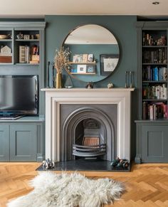 a living room filled with furniture and a fire place under a round mirror on the wall