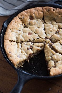 a chocolate chip pie in a cast iron skillet on a wooden table with a slice missing