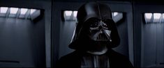 darth vader is standing in the dark room with his head turned to look like he's wearing a helmet