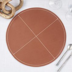 a table setting with utensils, wine glasses and an oval shaped placemat