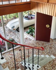 a staircase leading to a car parked in front of a window with glass doors on both sides