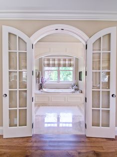 an open door leading to a bathroom with a tub in the corner and wooden floors